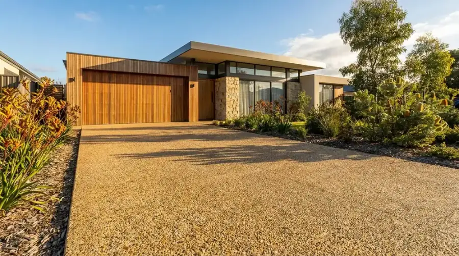 Exposed aggregate concrete driveway in a warm honey stone blend at a modern Perth home with a timber garage door