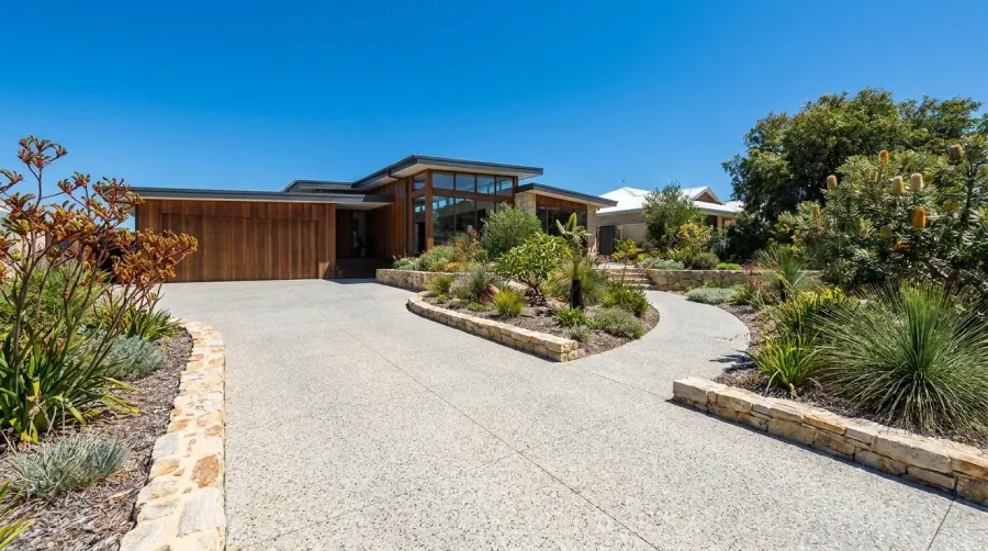 Wide exposed aggregate driveway and curved entry path with limestone garden walls at a Perth home