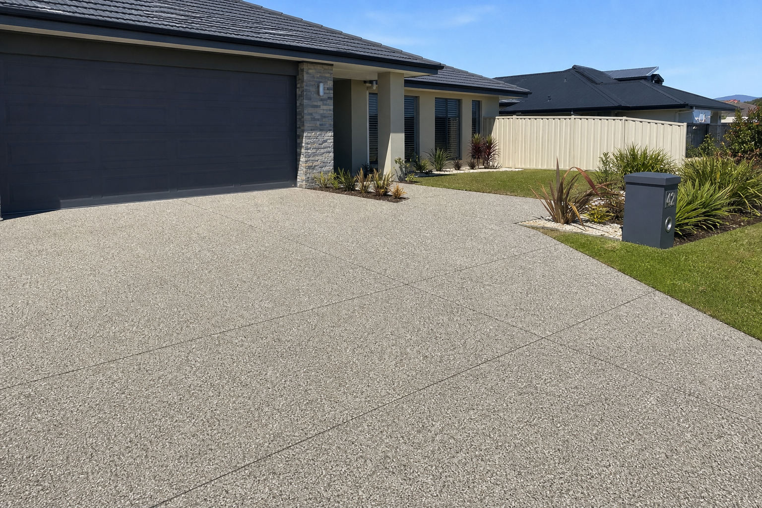 CoastCrete crew finishing an exposed aggregate driveway in a Perth suburb mid-afternoon, smooth grey stone surface, professional tools visible