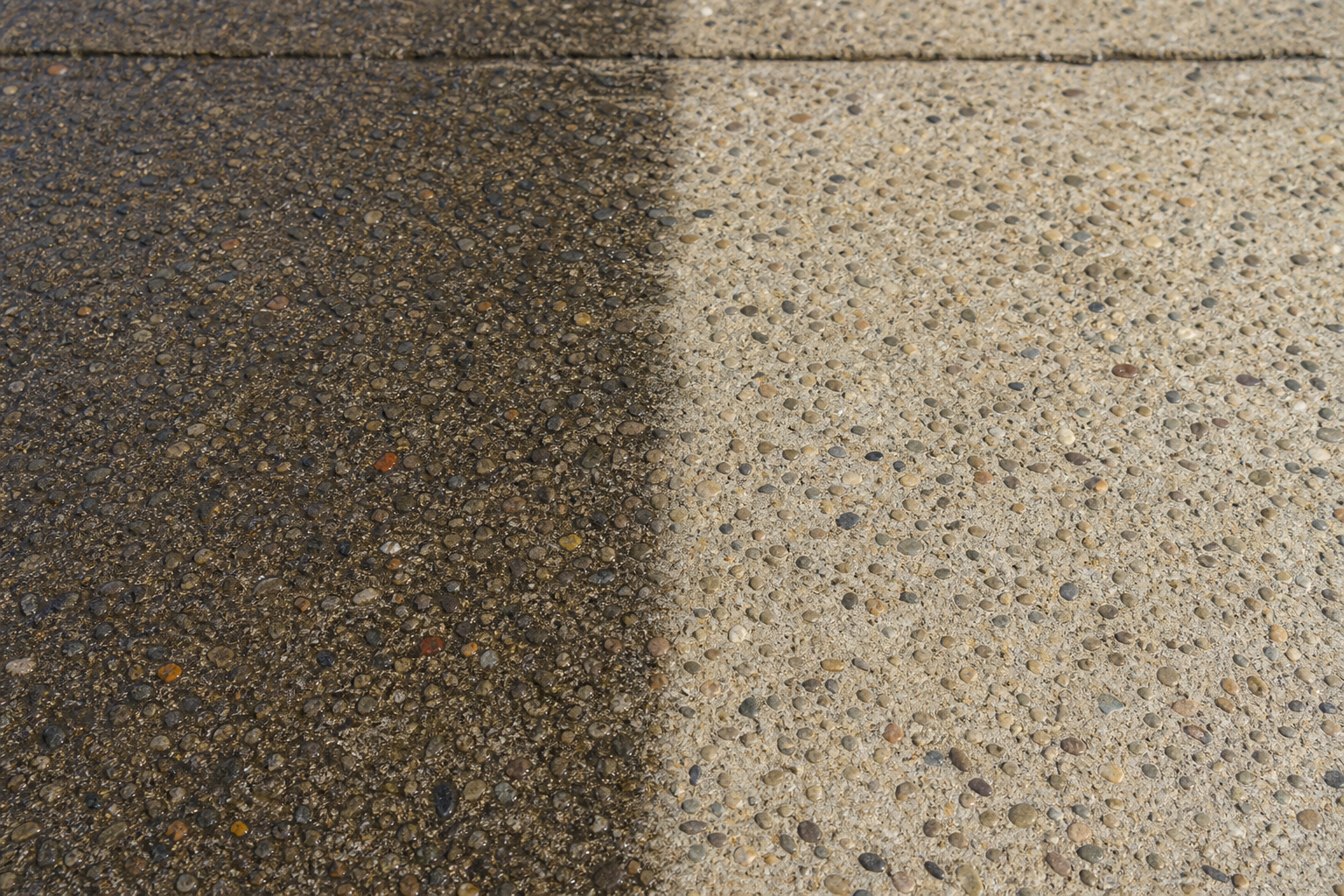 Close-up of exposed aggregate concrete surface partly cleaned and partly dirty, before-and-after contrast, no people, photorealistic