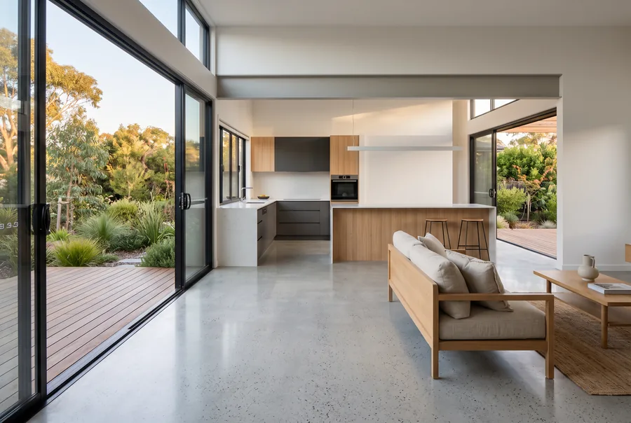 Honed concrete floor running through an open-plan Perth living and kitchen space out to a timber deck